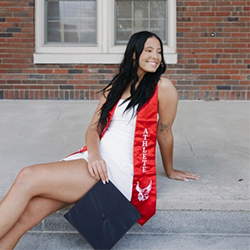 Sydney Yanak smiles with graduation sash and cap