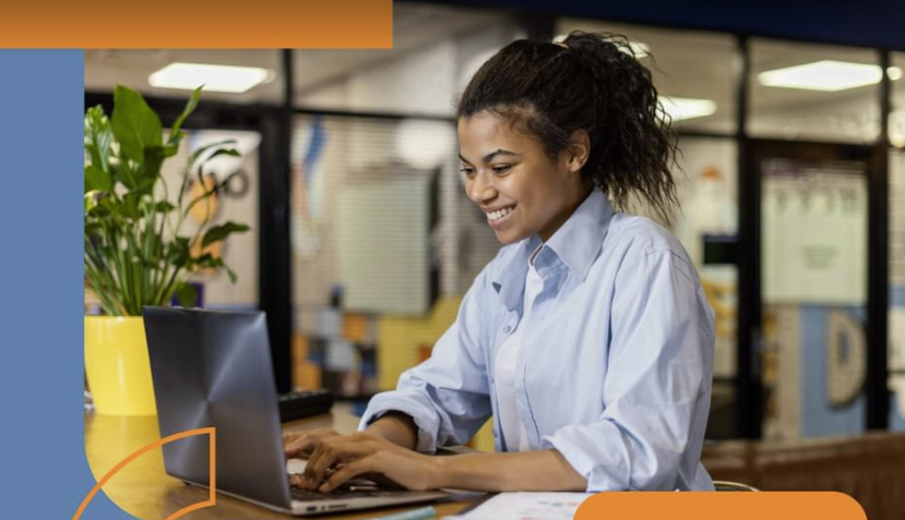 A young woman smiles and types at a laptop